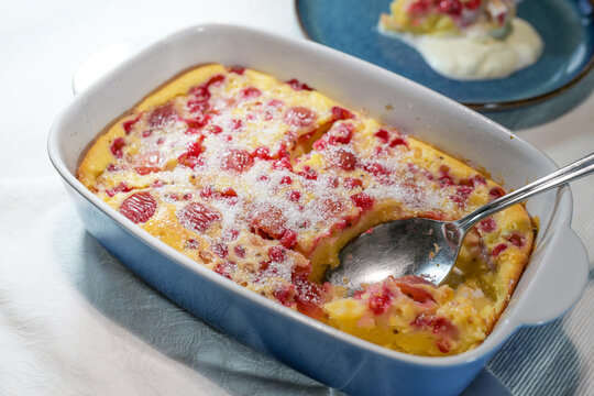 Sweet oven pancake with currants and cherries baked in a blue ceramic casserole, homemade dessert with summer fruits, light gray background, copy space