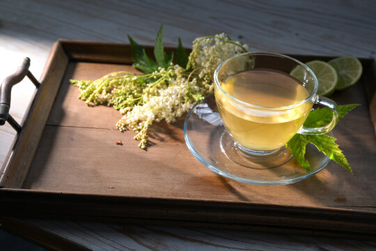 Meadowsweet tea on a small wooden tray, medicinal plant (Filipendula ulmaria) used to treat colds, copy space, selected focus