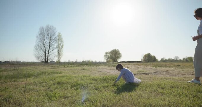 Young mother with child daughter spend time playing enjoying nature. 4K 10-bit