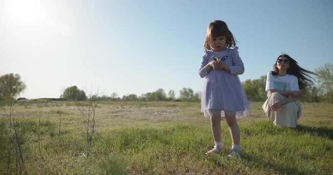 Young mother with child daughter spend time playing enjoying nature. 4K 10-bit