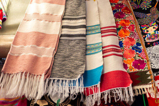 Colorful Mexican Textile Display with Embroidered Garments and Woven Shawls at Artisan Market