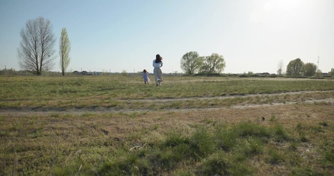 Young mother with child daughter spend time playing enjoying nature. 4K 10-bit