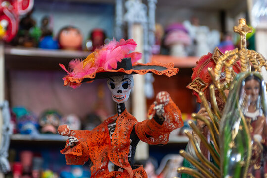 Handcrafted Catrina figurine with orange dress and feathered hat at Mexican artisan market