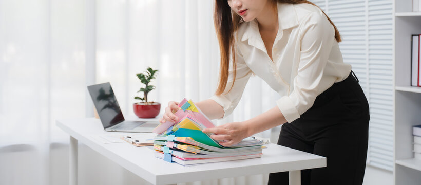 Organizing the Documents: A dedicated office worker is meticulously organizing the documentation, ensuring efficiency in workflow. Meticulous organization brings precision and attention to detail.	