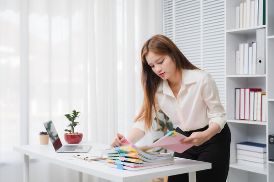 Organizing the Documents: A dedicated office worker is meticulously organizing the documentation, ensuring efficiency in workflow. Meticulous organization brings precision and attention to detail.	