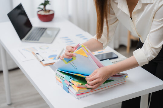 Organizing the Documents: A dedicated office worker is meticulously organizing the documentation, ensuring efficiency in workflow. Meticulous organization brings precision and attention to detail.	