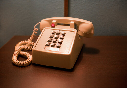 Peach color telephone on wooden table