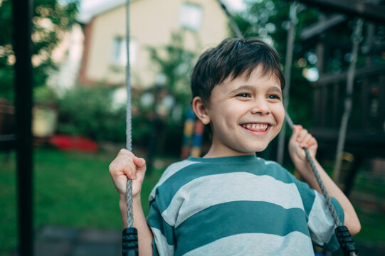 Happy boy enjoys swinging at the park during a summer day