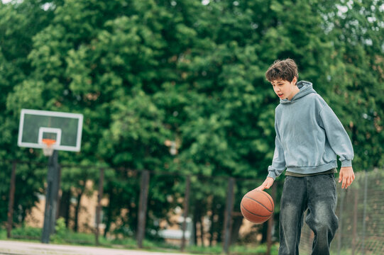 Teenage boy playing basketball outside