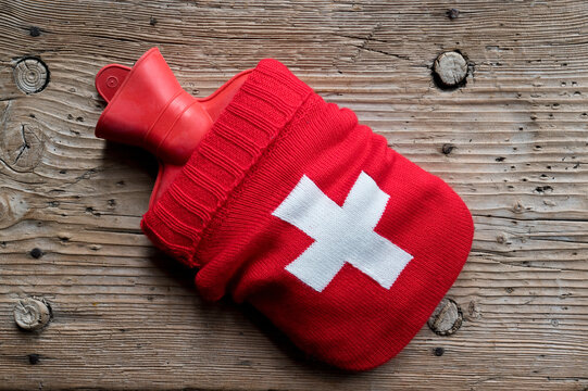 Hot water bottle in knitted sleeve with first aid symbol