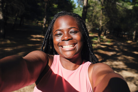 Happy young woman taking selfie in sunlight
