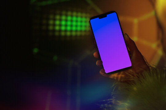 Hand holding glowing smartphone mockup in a dark neon night club