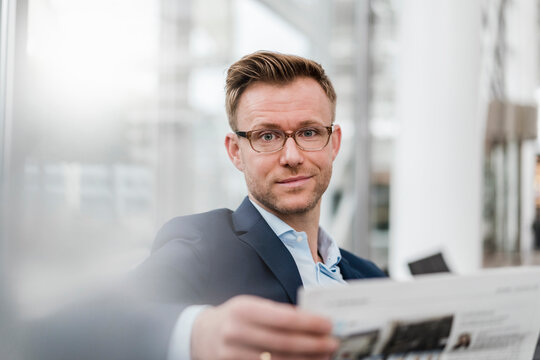 Businessman with newspaper sitting in city