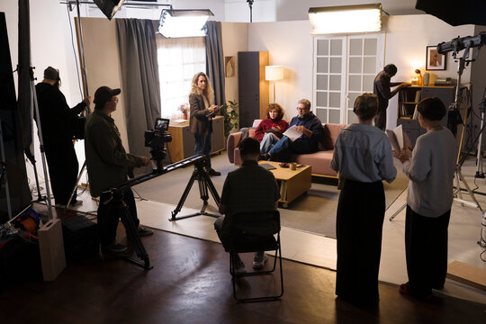 A film crew shoots a video scene with an actor and actress indoors