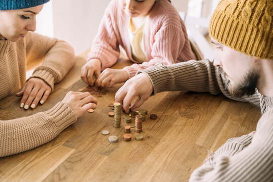 Poor family with winter hats sitting at table counting coins