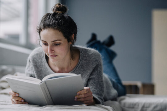Portrait of young woman reading book at home