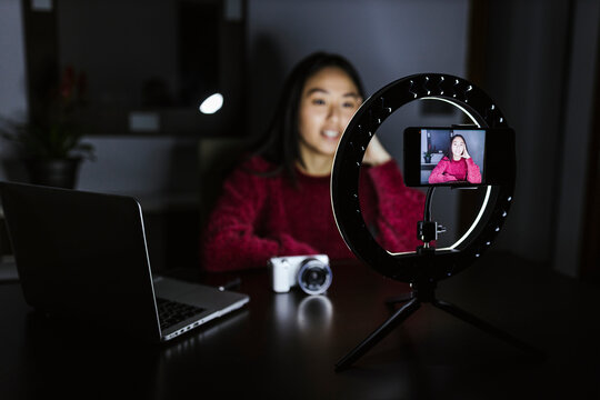 Female influencer vlogging about new camera in darkroom