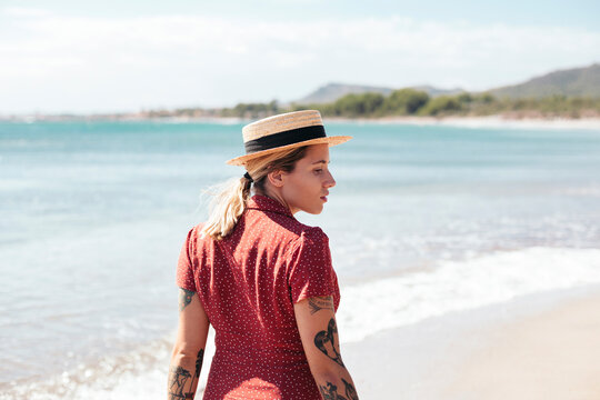 Spain, Mallorca, pensive young woman with tattoos on the beach