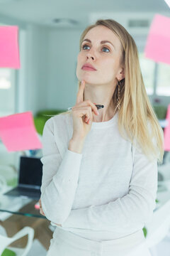 Thoughtful female entrepreneur looking at adhesive note in office
