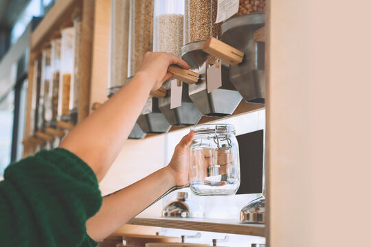 Customer filling lentils in glass jar at zero waste shop