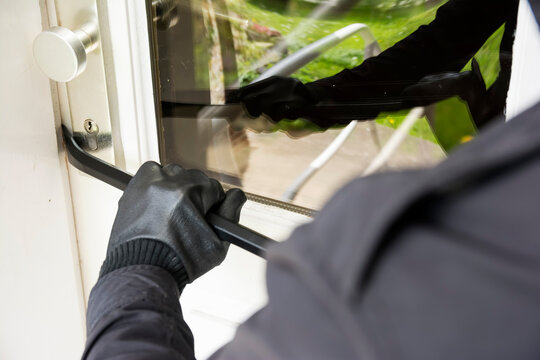 Male burglar forces house door open with crowbar during daytime