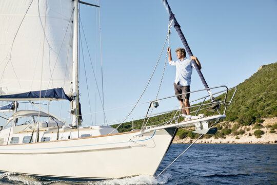 Man standing on bow of his sailing boat looking at distance