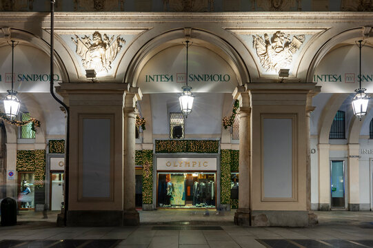 Torino, Italia - 13/12/2014 - piazza San Carlo. Portici storici con colonne, archi, luci festive e vetrina di negozio. Scena notturna elegante ideale per temi urbani, architettura e lifestyle.