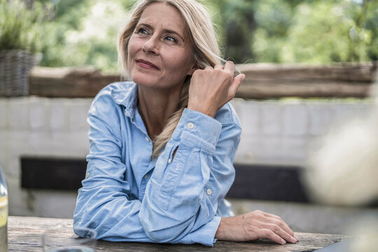 Mature woman sitting on terrace, thinking