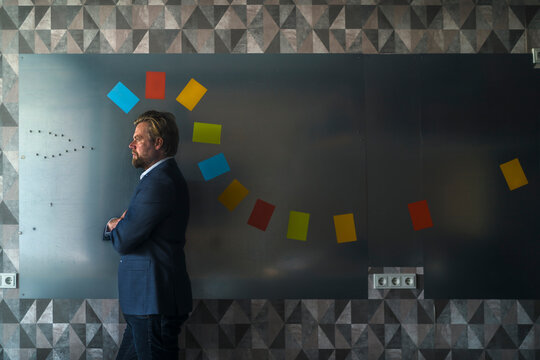 Businessman standing in front of magnet wall with a colorful headdress, made from sticky notes