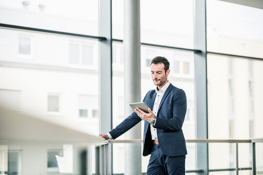 Businessman standing in office building, using digital tablet