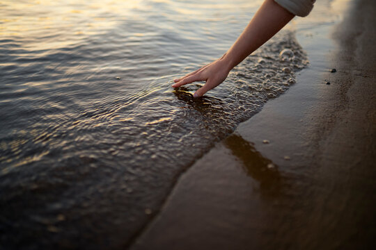 Woman touches the river water at sunset