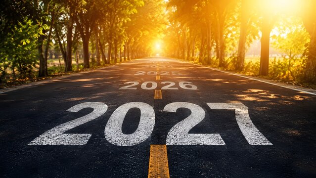 Numbers 2027 painted on an asphalt road leading into a bright golden sunrise with trees on the sides representing a new year and future goals journey