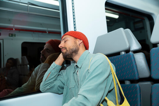 Tired man sleeps on a metro train during his daily commute