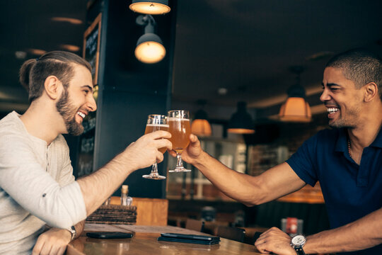 Two happy men in a bar clinking beer glasses