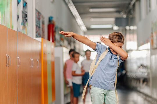 Boy dabbing in school hallway showing happiness