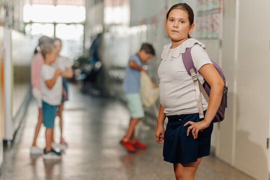 School girl standing in hallway with backpack
