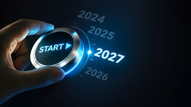 Person hand turning a glowing start button to select the year 2027 on a digital futuristic dashboard interface to represent the beginning of a new future and business goals for the year