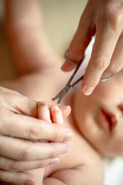 Mother caring for newborn baby during daily nail trimming routine at home