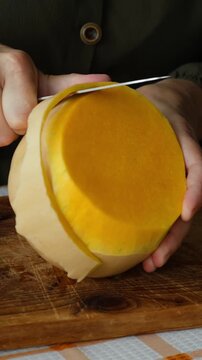 Vertical video. Female hands peeling pumpkin. Preparing autumn food. Cooking pumpkin soup or cake.