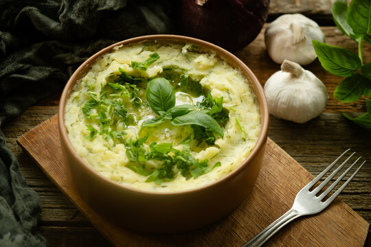 Bowl of mashed potatoes with fresh greenery on rustic table