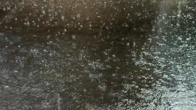 Close up of heavy rain splashes on dark asphalt motion video footage