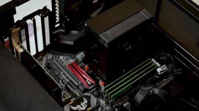 A wide close-up view of the interior of a desktop computer case showing the motherboard, RAM sticks, and various hardware components.
