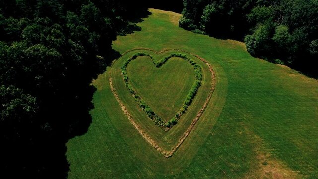 Drone view slowly dropping down in front of a big green heart in a pasture in Berlin, Massachusetts.