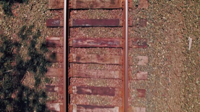 Aerial drone bird's eye view slowly tracking forward over rail road tracks.