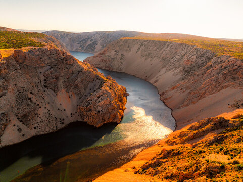 View of the Zrmanja River Canyon in Croatia, with winding turquoise waters cutting through limestone cliffs. A scenic natural wonder popular for kayaking and hiking