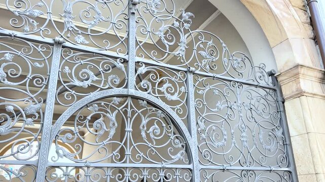 An elegant wrought iron gate with intricate scrollwork frames the entrance to a historic courtyard in L&ouml;rrach, Germany. Slow downward tilt filmed from close range.