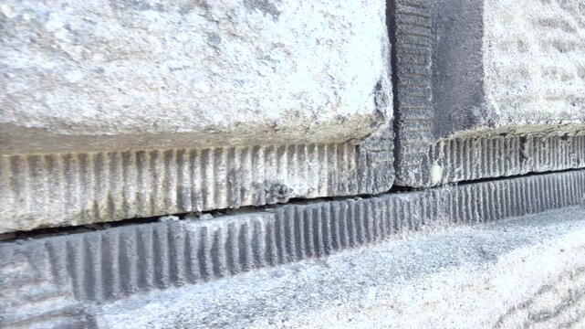 A close-up tracking shot moves smoothly along a textured concrete block wall, highlighting the ribbed surface, mortar joints, and geometric construction pattern. Close-up tracking shot moving.