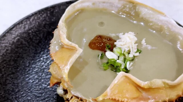 Close-up of a crab shell filled with rich and creamy crab tomalley, beautifully presented as a premium seafood delicacy in Japanese cuisine.