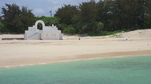 白い砂浜に建つギリシャ風のモニュメントとエメラルドグリーンの海