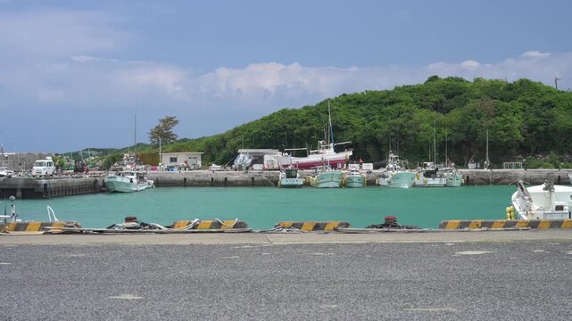 エメラルドグリーンの海に漁船が停泊するのどかな港の風景